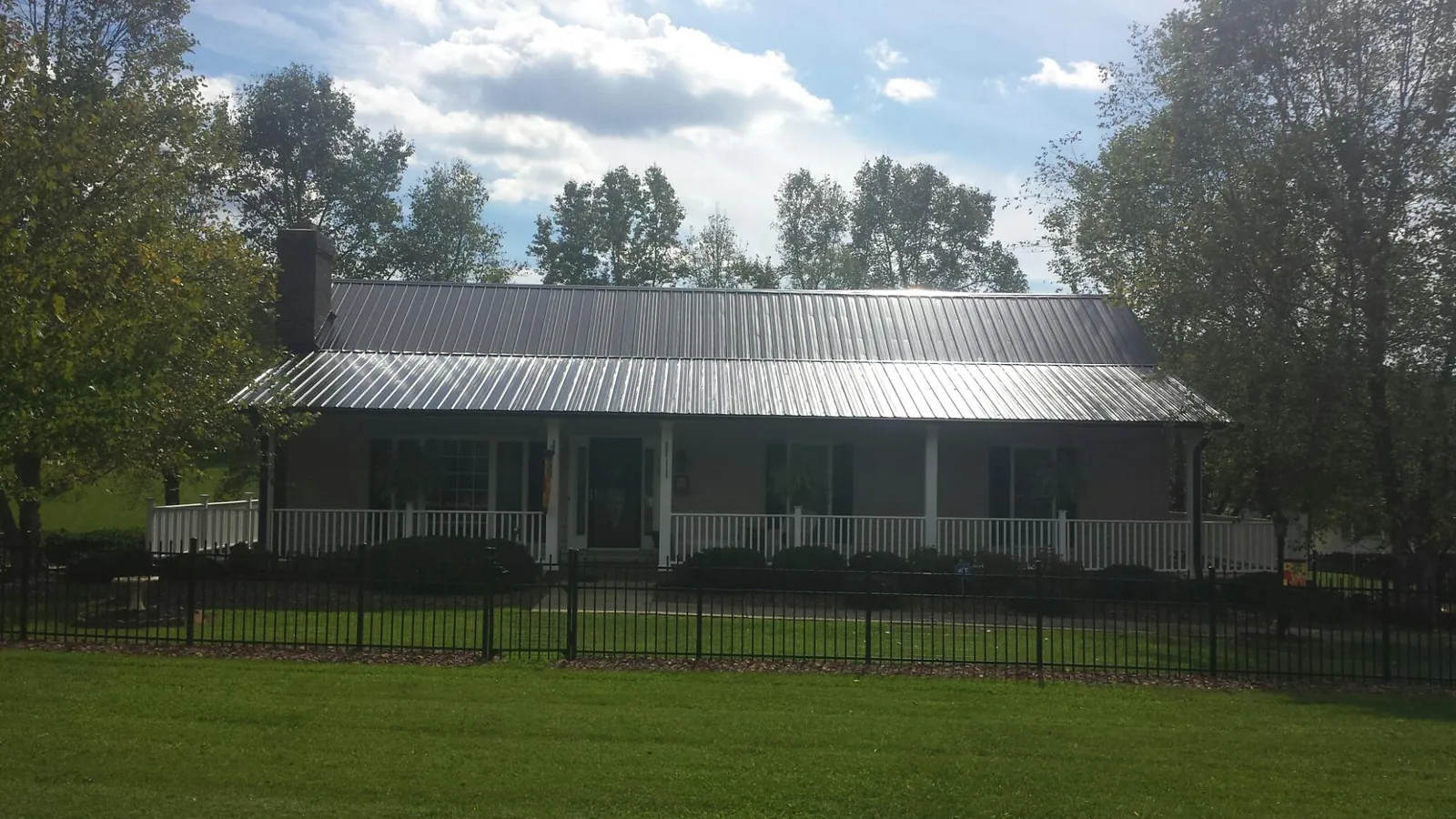 Gray metal roof on a brick ranch with a full width front porch — Gutter Guard Installation work by our crew in Augusta